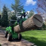 PrimeCut Tree Service uses a low-impact log loader to carefully move a large tree section across a lawn in Omaha, protecting the grass.